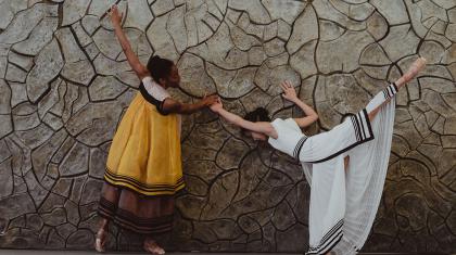 Two female dancers reach out to a cracked wall