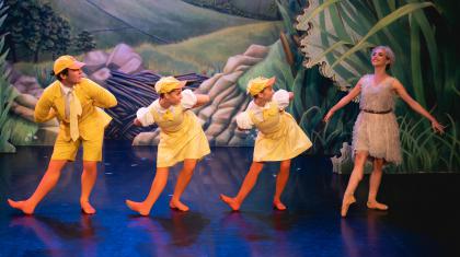 Four dancers dressed as ducklings in a line