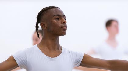 A young man in ballet class with arms raised