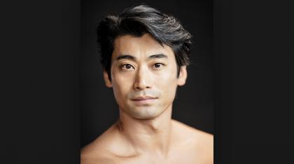 Photo of the head and shoulders of dancer Ryoichi Hirano against a very dark background