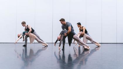 Three male/female couples him supporting her by the waist as she as she leans back, draped over his hold and en pointe.