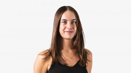 A headshot of a woman looking forward with dark brown hair and a black top