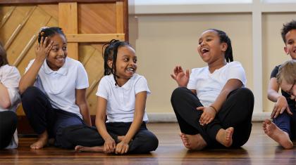 Three girls sat on the floor cross-legged, laughing