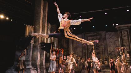 Leaping his above the stage while other cast members look on.