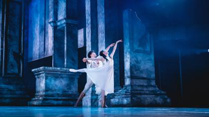 In cool blue light, Romeo and Juliet dance lovingly and closely across the stage