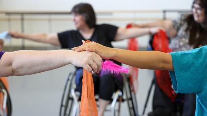 Clasped hands holding an orange silk and a pink feather