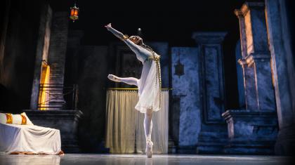 Juliet in white standing en pointe, happily reaching upwards