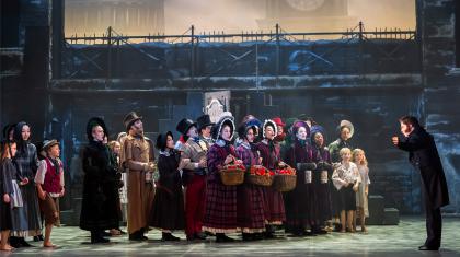 A photo of a group of dancers singing in Victorian era clothing