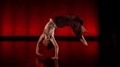 Dancer mid back-flip, hands against the floor, back arched, feet off the ground