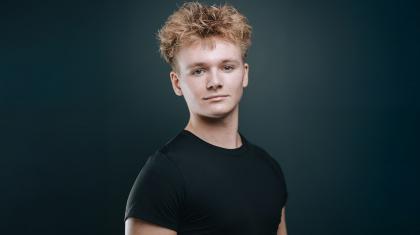 Portrait of shoulders and head  of man wearing a black T-shirt, short blond hair and looking directly at the observer