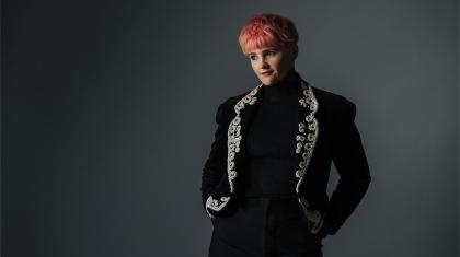Person in a black jacket with silver trim, and pink hair
