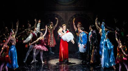 Clara's father carries her while she sleeps, the magical characters from her dreams look on