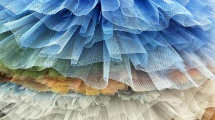 A vertical stack of tutus ranging from white to blue