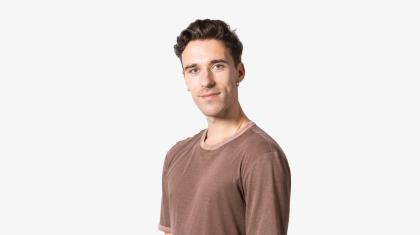 A headshot of a man with dark hair in a brown tshirt