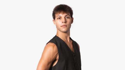 A man with dark hair stood in sideways wearing a black waistcoat