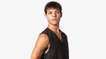 A man with dark hair stood in sideways wearing a black waistcoat