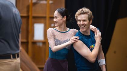 Two dancer in rehearsal smiling at something happening beyond the frame