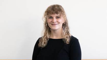 Woman with long, blonde, curly hair smiles directly at the camera