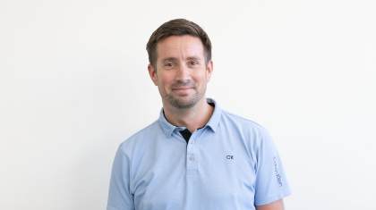 Man with short brown hair smiles closed-mouth at the camera
